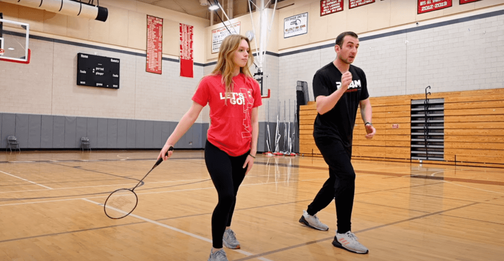 A student practices her badminton skills with a teacher.